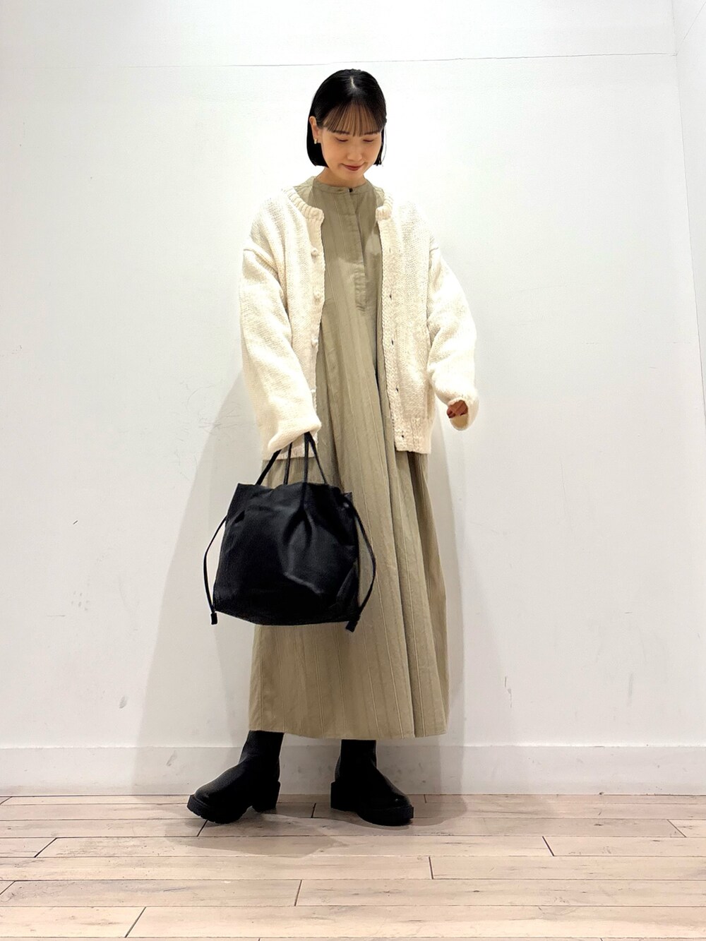 ホワイト系のニット/セーター、ブラック系のブーツ、ブラック系のショルダーバッグを着用したレディースの秋コーディネートの2枚目の写真