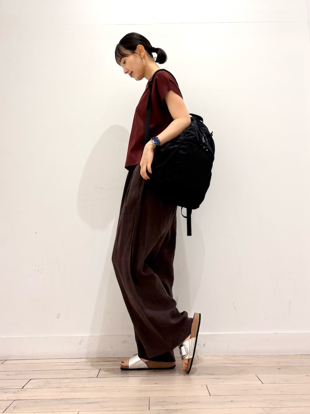ブラウン系のその他パンツ、ブラック系のバックパック/リュック、シルバー系のサンダルを着用したレディースの夏コーディネートの3枚目の写真