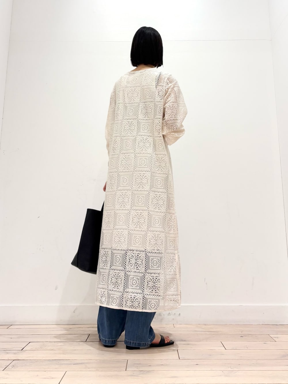 ベージュ系のワンピース、ブルー系のデニムパンツ、ブラック系のトートバッグを着用したレディースの春コーディネートの5枚目の写真