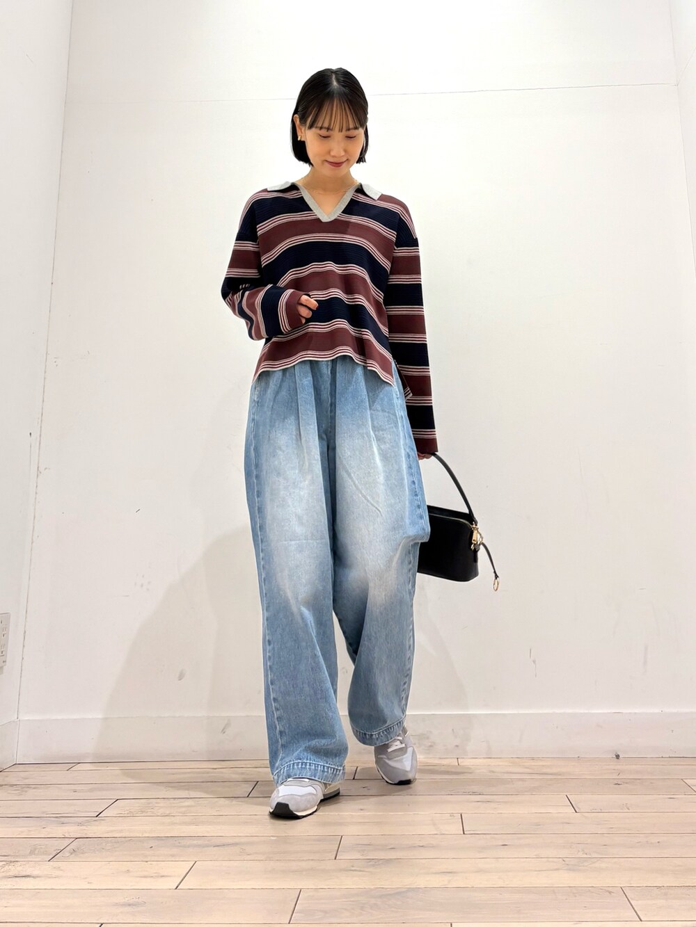 ブルー系のニット/セーター、ブルー系のデニムパンツ、ブラック系のショルダーバッグを着用したレディースの秋コーディネートの4枚目の写真