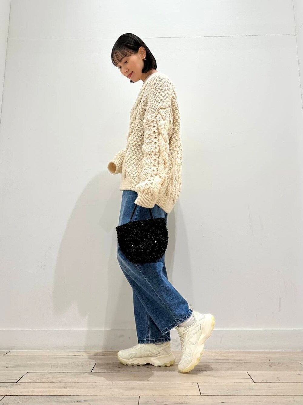 ブラック系のショルダーバッグ、ホワイト系のスニーカー、ブラック系のその他アウターを着用したレディースの冬コーディネートの3枚目の写真