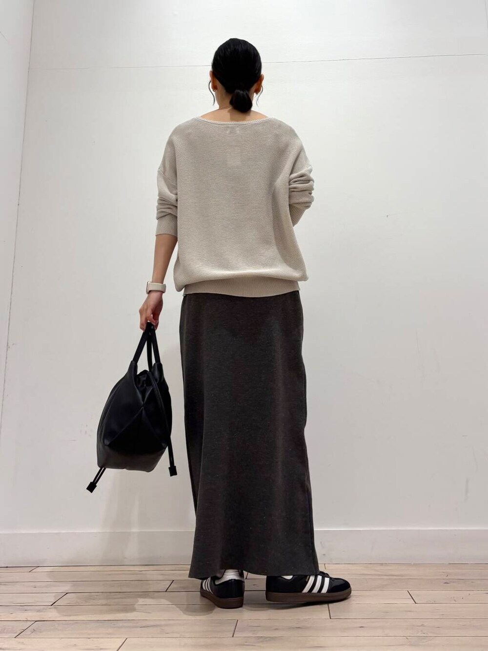ブラック系のショルダーバッグ、グレー系のニット/セーター、グレー系のスカートを着用したレディースの春コーディネートの4枚目の写真