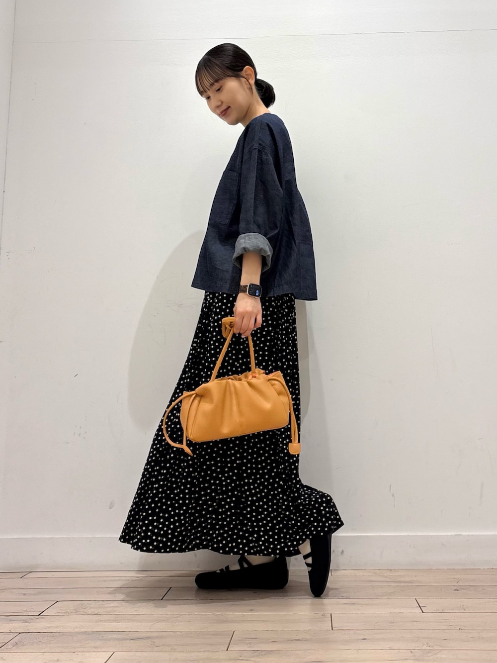 ブルー系のシャツ/ブラウス、ブラック系のスカート、オレンジ系のショルダーバッグを着用したレディースの春コーディネートの2枚目の写真