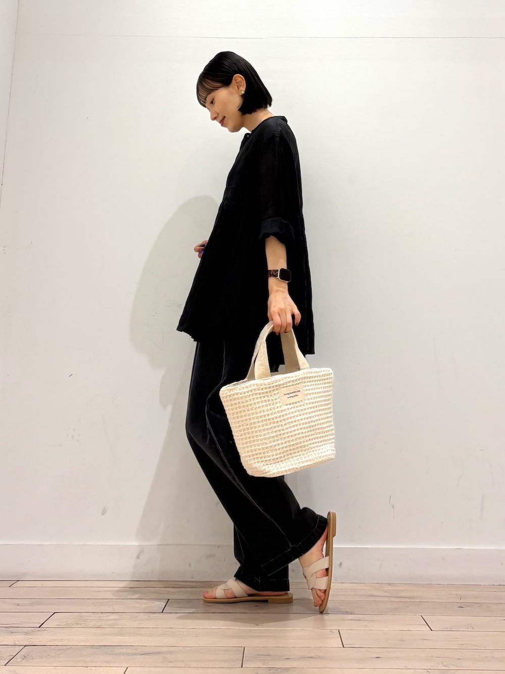 ブラック系のデニムパンツ、ホワイト系のトートバッグ、ホワイト系のサンダルを着用したレディースの春コーディネートの4枚目の写真