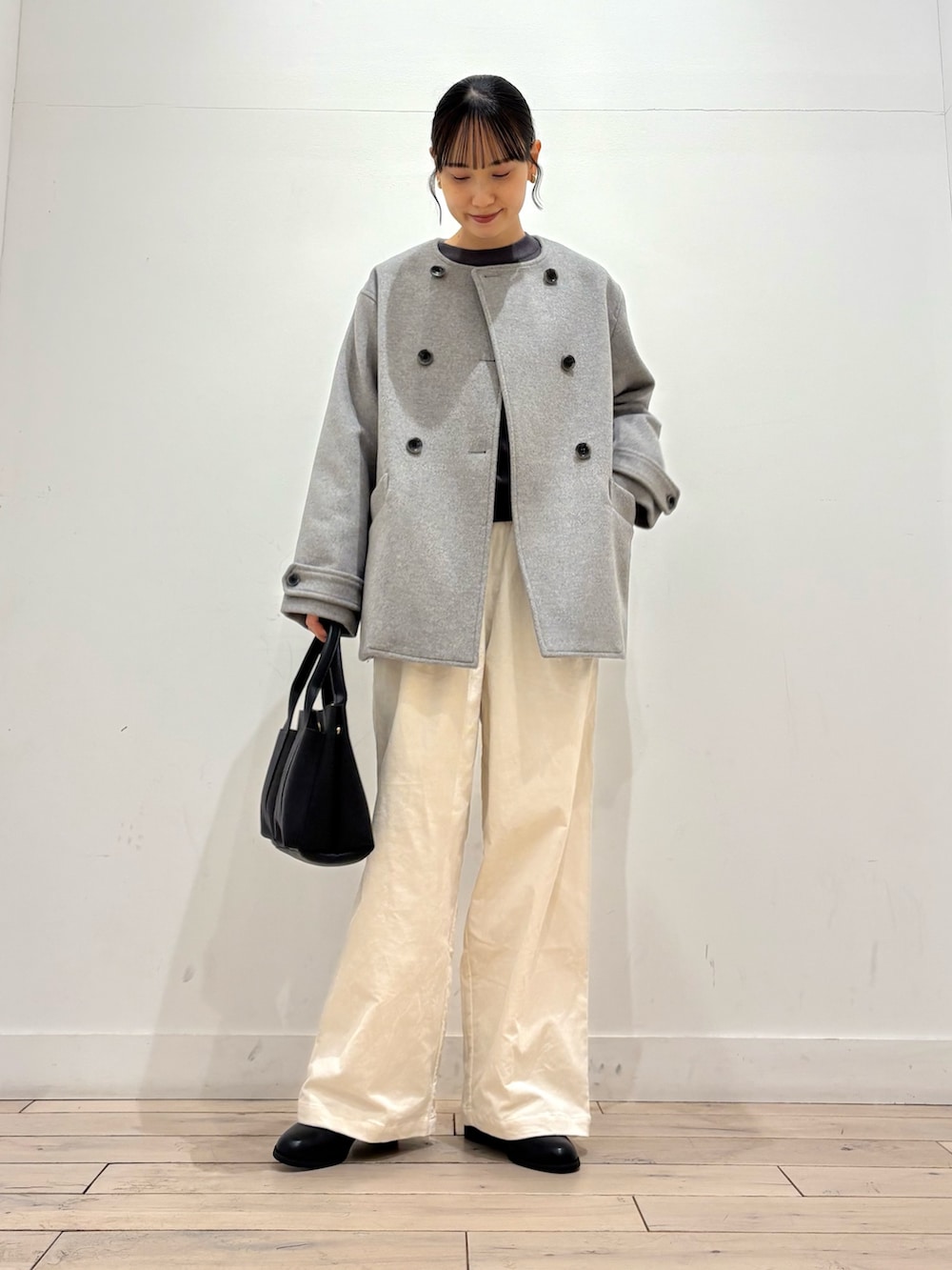 グレー系のピーコート、グレー系のニット/セーター、ブラック系のブーツを着用したレディースの冬コーディネートの3枚目の写真