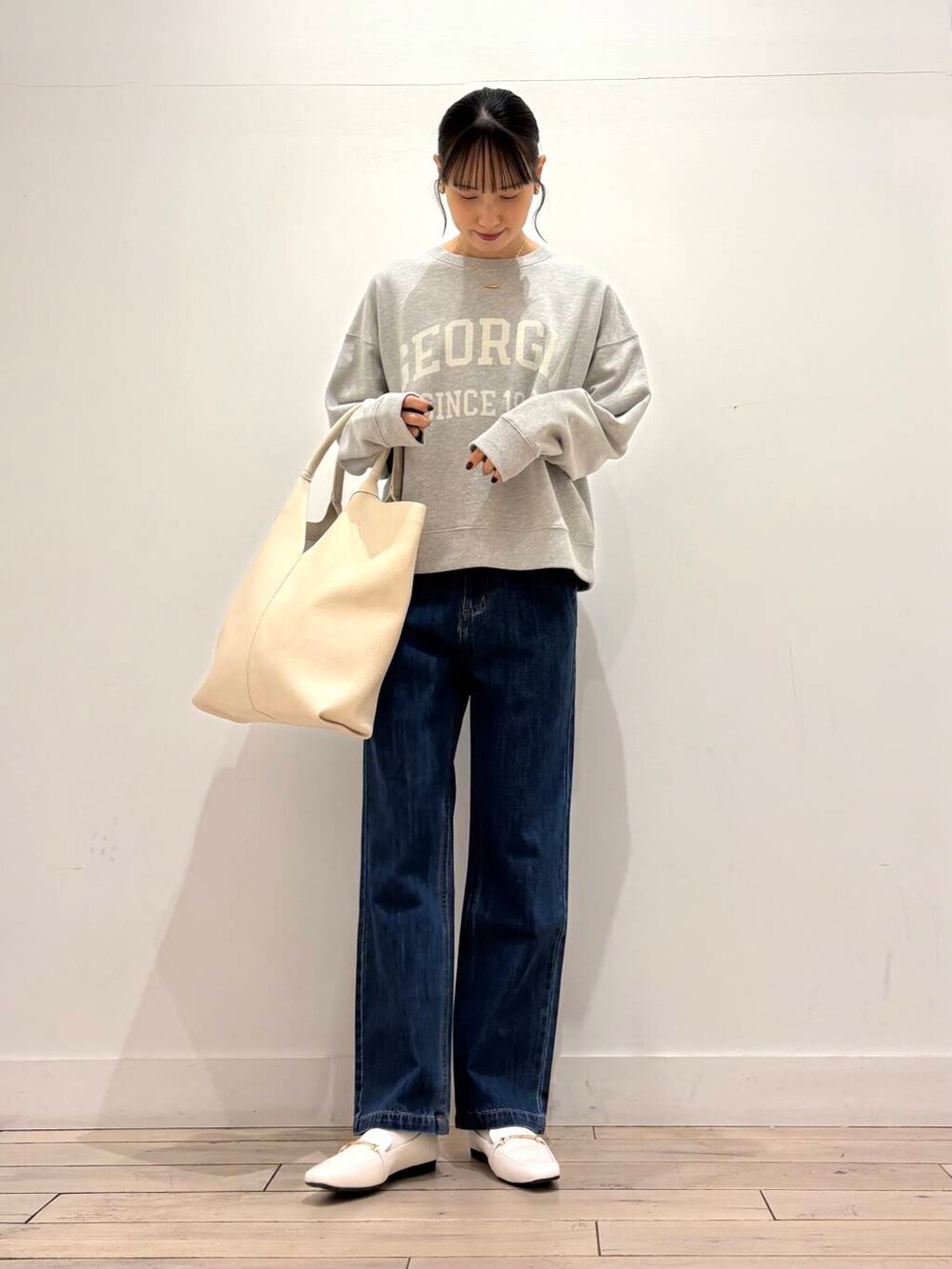 ブルー系のデニムパンツ、ブラック系のマウンテンパーカー、ホワイト系のローファーを着用したレディースの春コーディネートの5枚目の写真