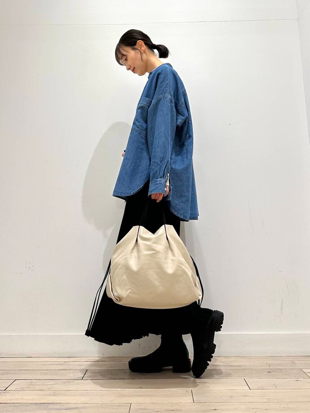 ホワイト系のトートバッグ、ブラック系のブーツ、ベージュ系のTシャツ/カットソーを着用したレディースの冬コーディネートの3枚目の写真