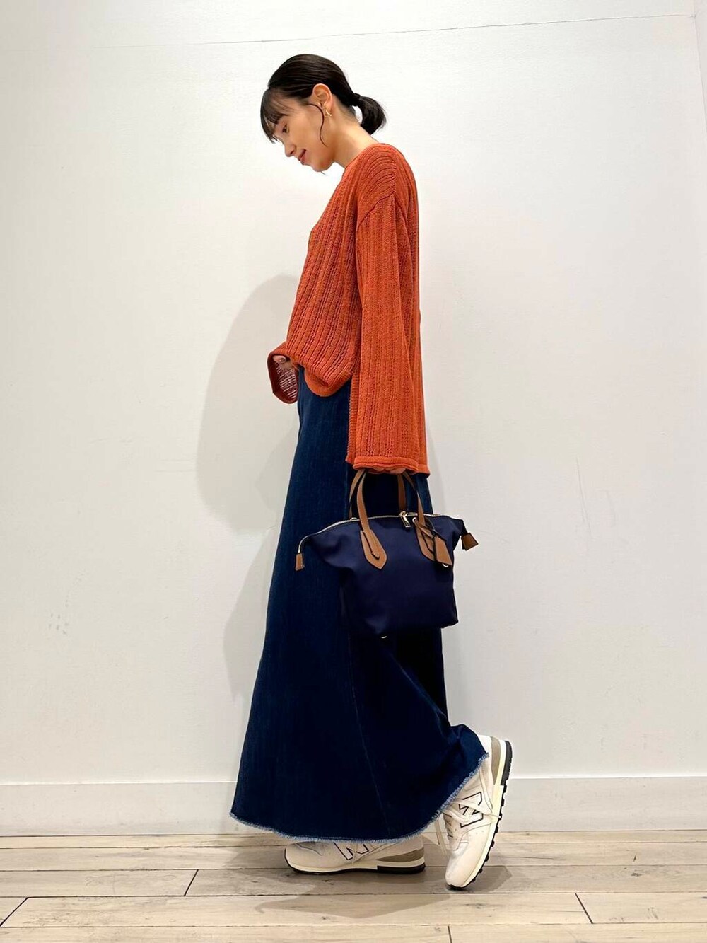 ブルー系のトートバッグ、ホワイト系のスニーカー、オレンジ系のニット/セーターを着用したレディースの夏コーディネートの3枚目の写真