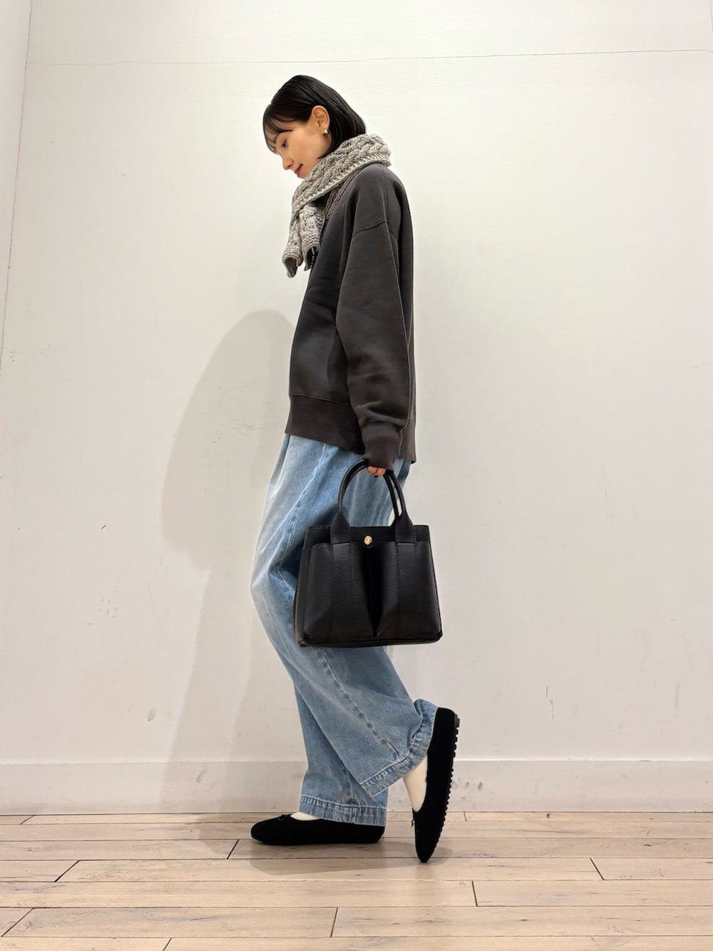 グレー系のスウェット、ブルー系のデニムパンツ、ブラック系のトートバッグを着用したレディースの冬コーディネートの3枚目の写真