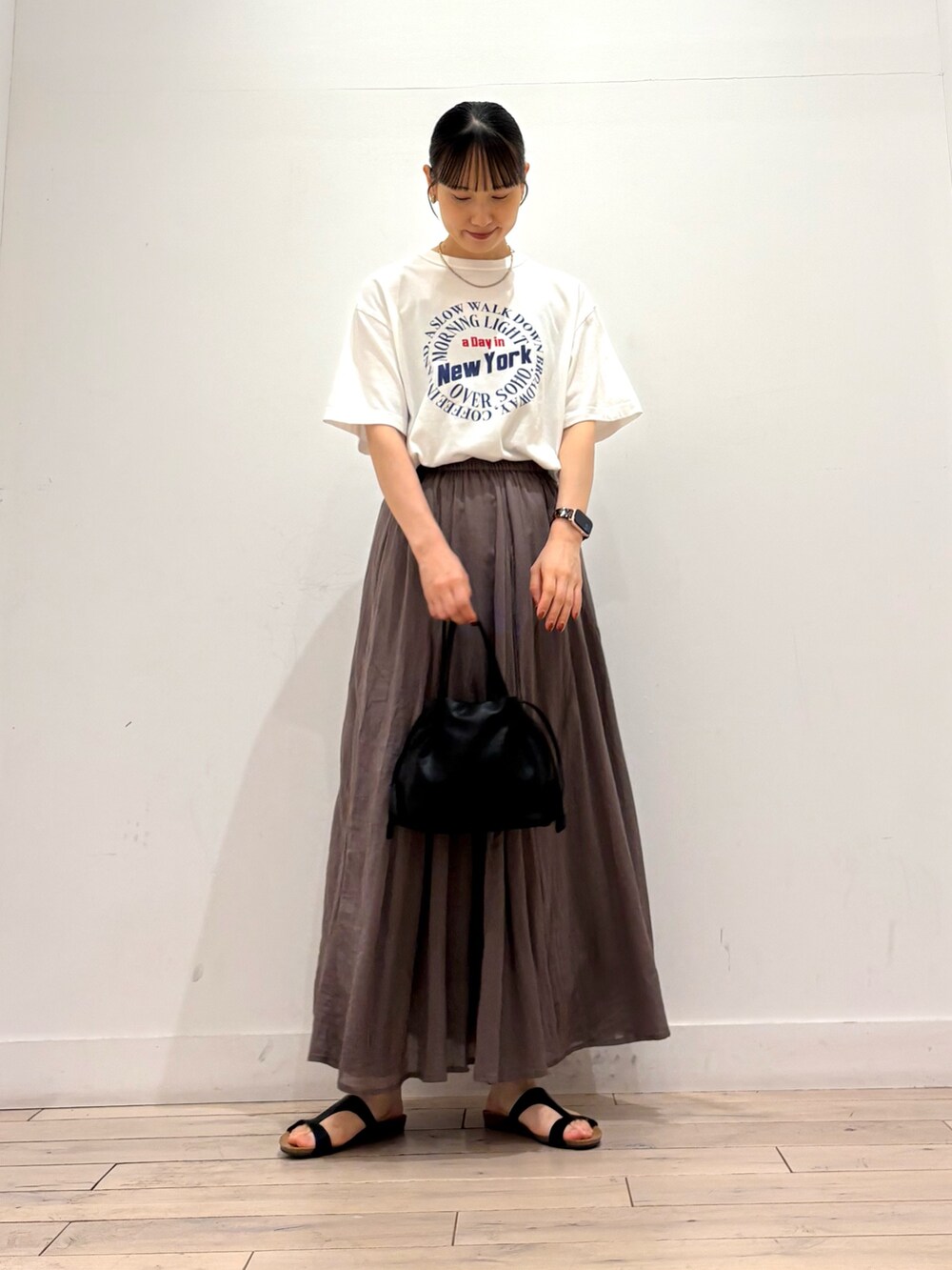 ホワイト系のTシャツ/カットソー、グレー系のスカート、ブラック系のショルダーバッグを着用したレディースの夏コーディネートの2枚目の写真