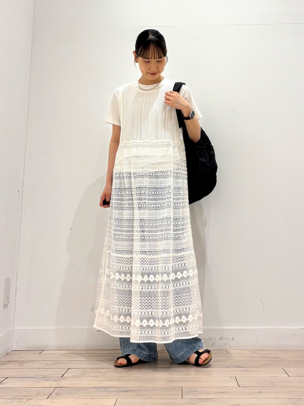 ホワイト系のワンピース、ブラック系のバックパック/リュック、ブラック系のサンダルを着用したレディースの夏コーディネートの2枚目の写真