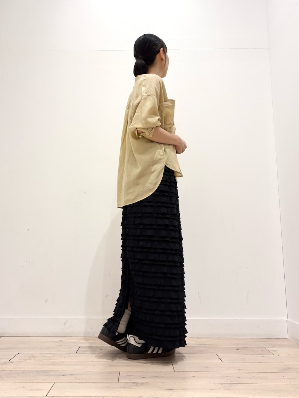 イエロー系のシャツ/ブラウス、ブラック系のスカート、ベージュ系のトートバッグを着用したレディースの夏コーディネートの2枚目の写真