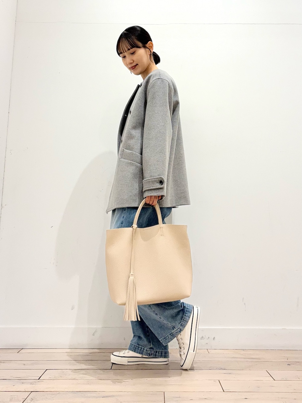 グレー系のピーコート、ブルー系のデニムパンツ、ホワイト系のトートバッグを着用したレディースの冬コーディネートの4枚目の写真