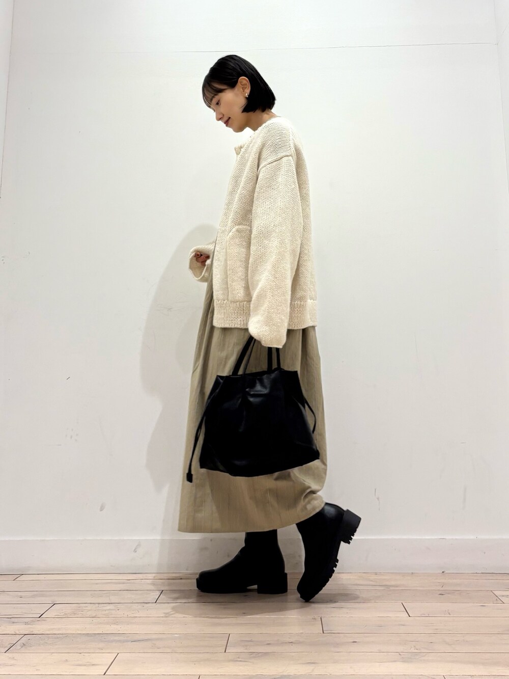 ホワイト系のニット/セーター、ブラック系のブーツ、ブラック系のショルダーバッグを着用したレディースの秋コーディネートの3枚目の写真