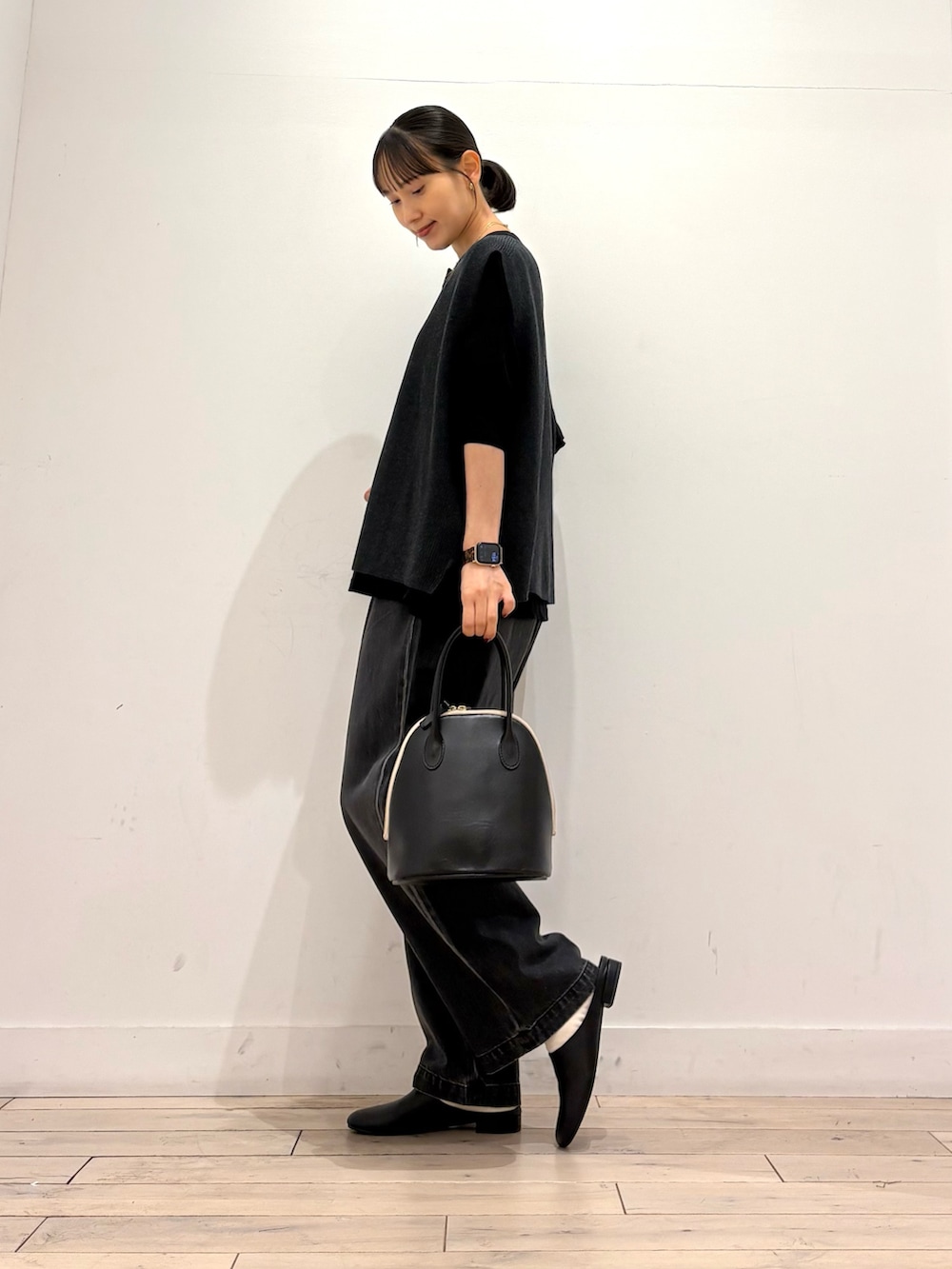 グレー系のベスト、ブラック系のTシャツ/カットソー、ブラック系のハンドバッグを着用したレディースの秋コーディネートの2枚目の写真