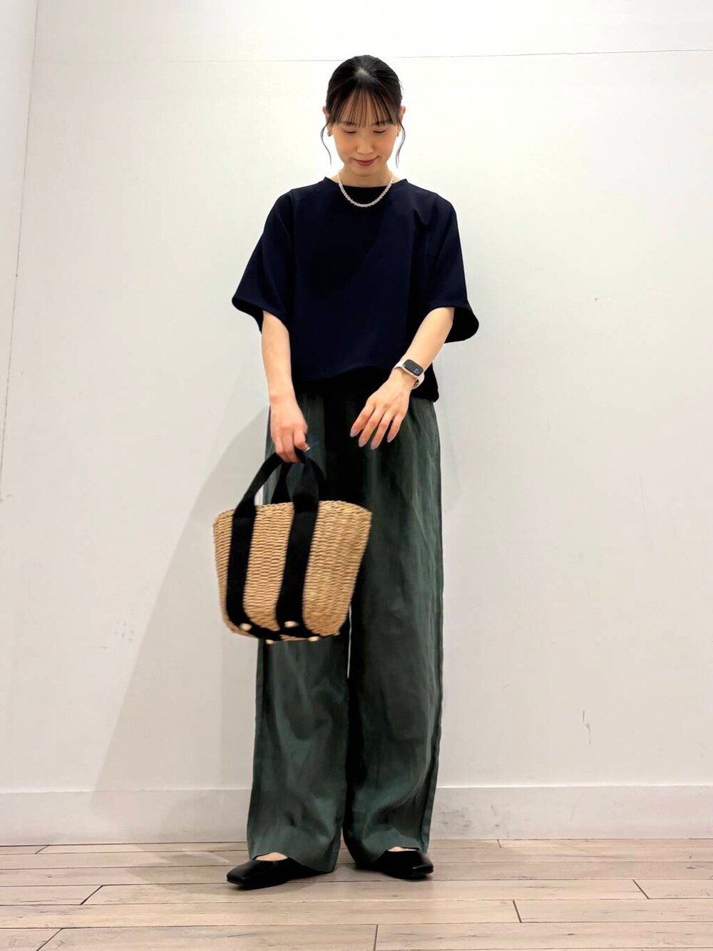ベージュ系のハンドバッグ、ブラック系のパンプス、グリーン系のその他パンツを着用したレディースの春コーディネートの2枚目の写真