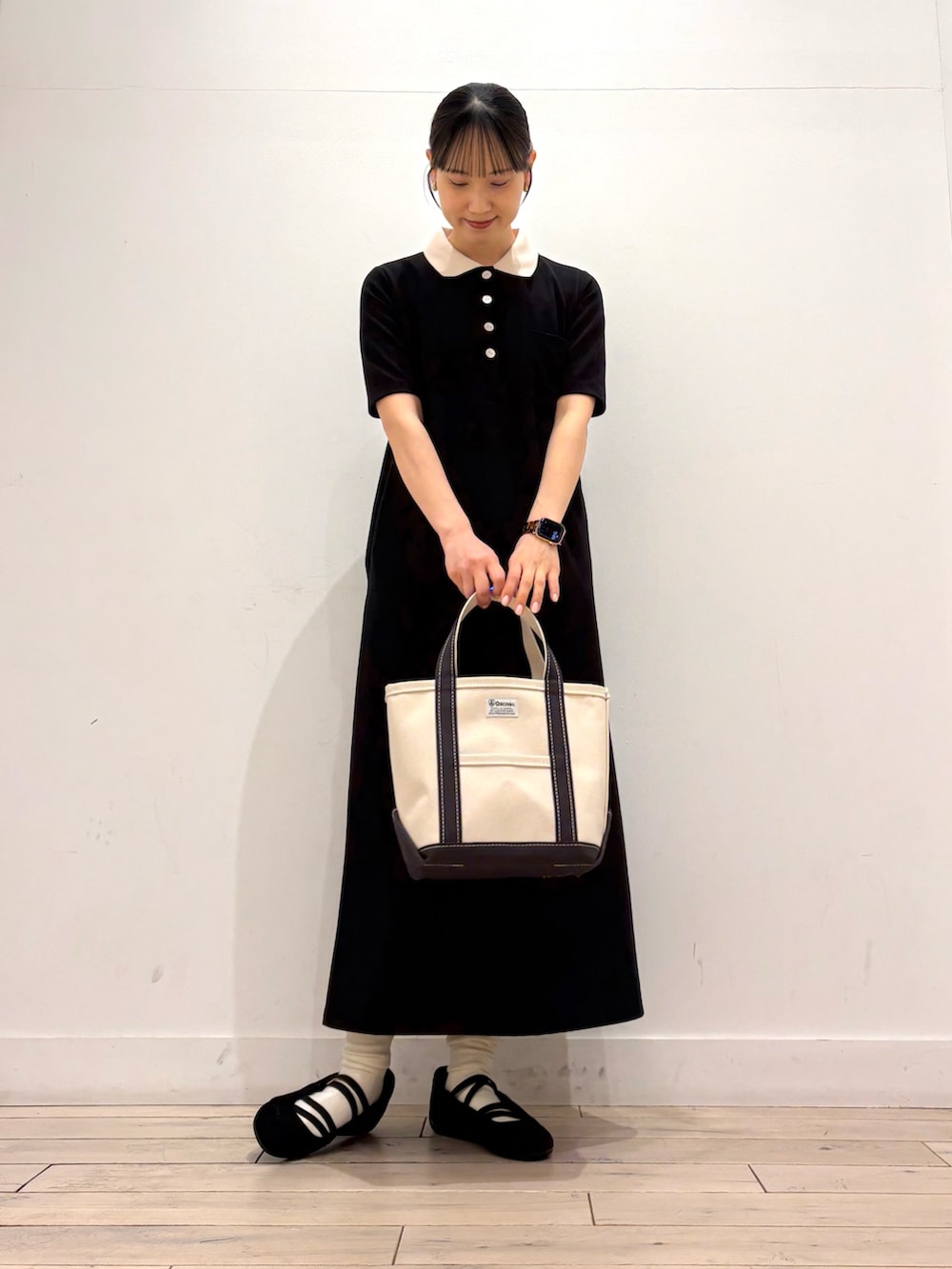 ブラック系のワンピース、グレー系のトートバッグ、ブラック系のスニーカーを着用したレディースの春コーディネートの2枚目の写真