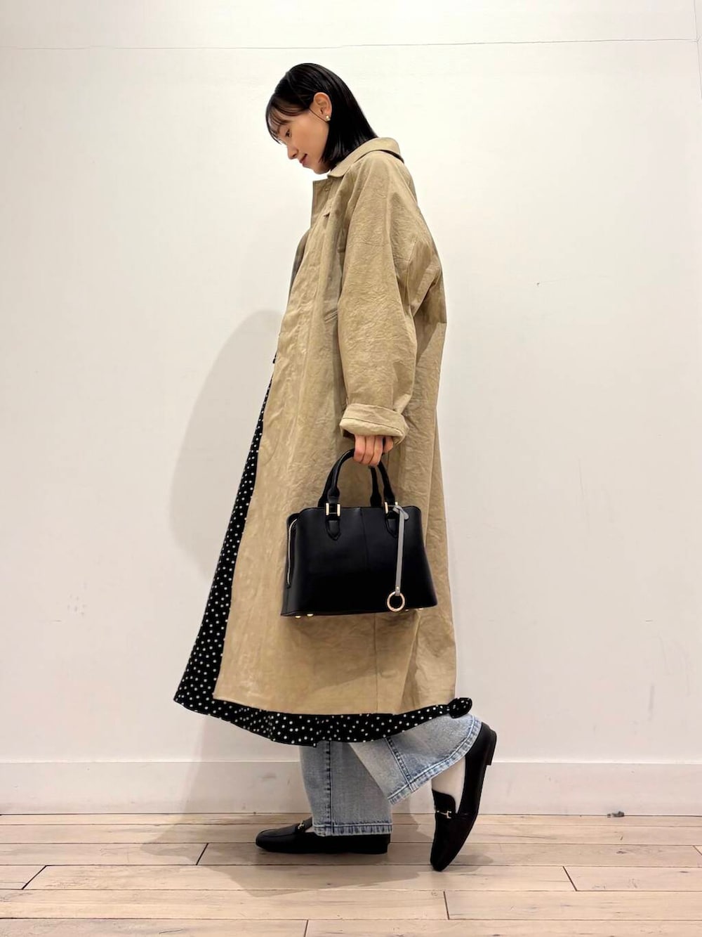 ブラック系のハンドバッグ、ブルー系のデニムパンツ、ブラック系のワンピースを着用したレディースの春コーディネートの6枚目の写真