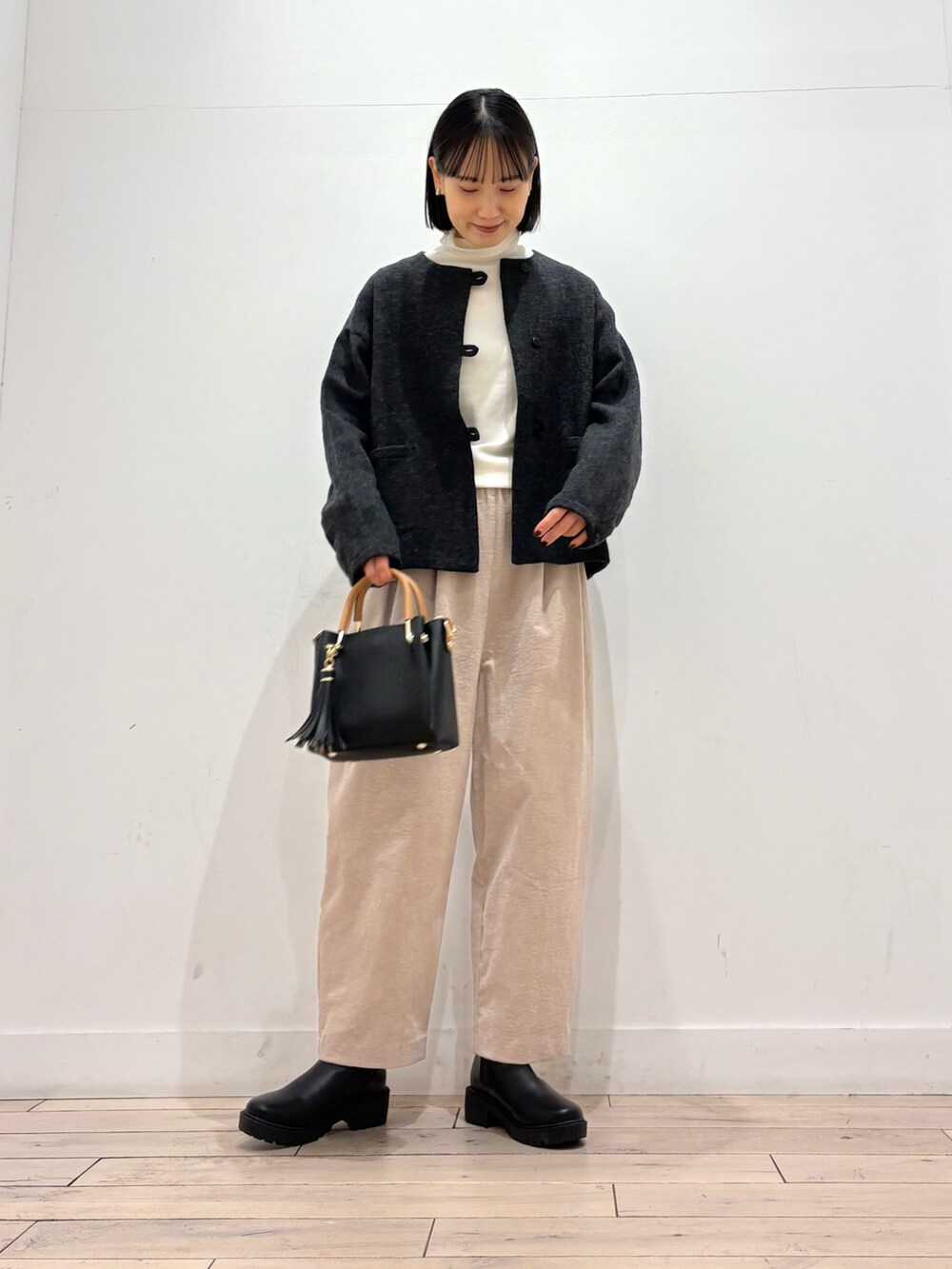 グレー系のノーカラージャケット、ホワイト系のTシャツ/カットソー、ブラック系のブーツを着用したレディースの秋コーディネートの2枚目の写真