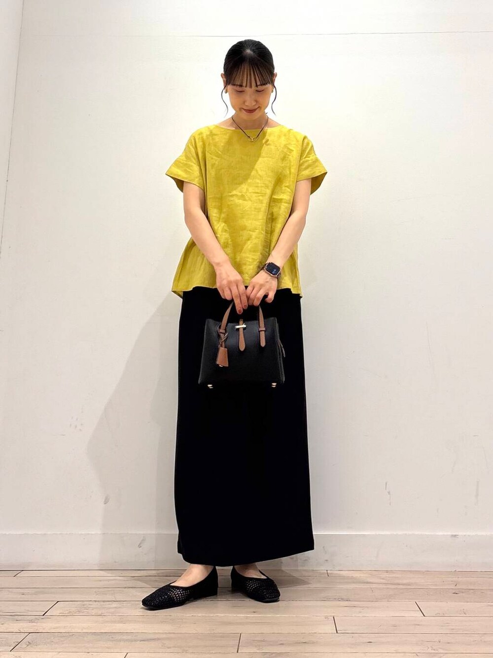 ブラック系のハンドバッグ、ブラック系のバレエシューズ、イエロー系のシャツ/ブラウスを着用したレディースの夏コーディネートの2枚目の写真