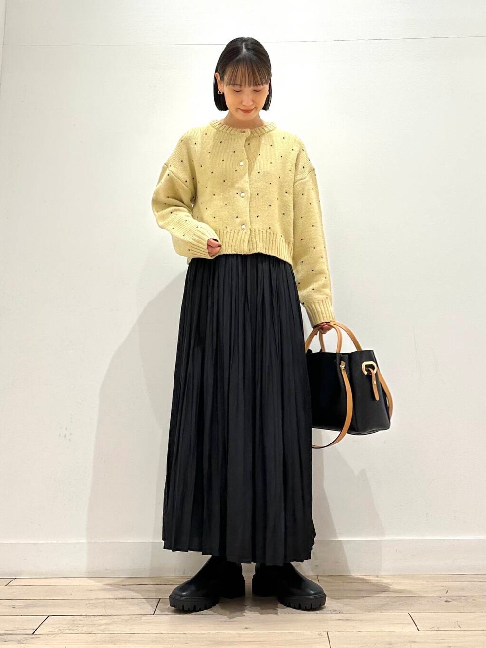 ブラック系のトートバッグ、ブラック系のブーツ、ブラック系のスカートを着用したレディースの秋コーディネートの2枚目の写真