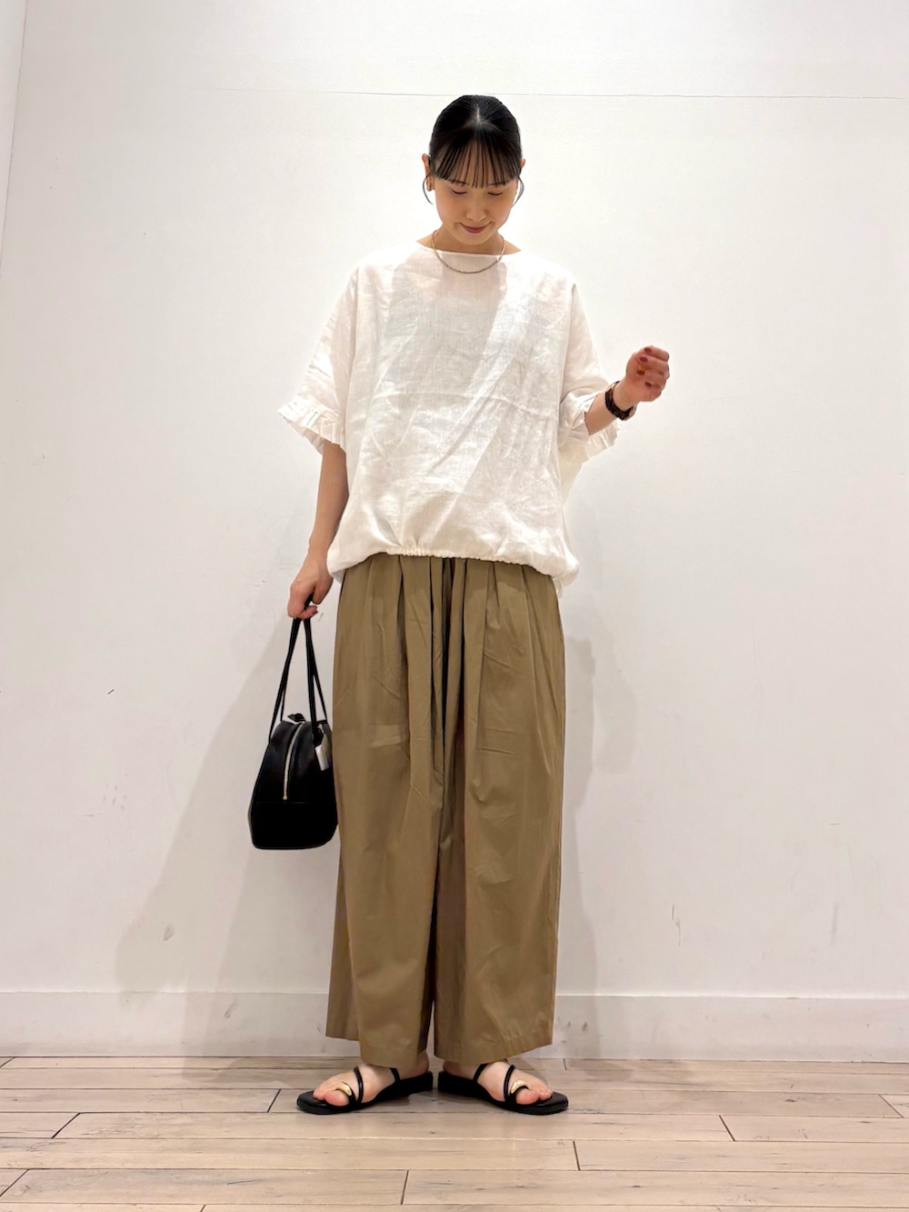ベージュ系のその他パンツ、ブラック系のボストンバッグ、ブラック系のサンダルを着用したレディースの夏コーディネートの2枚目の写真