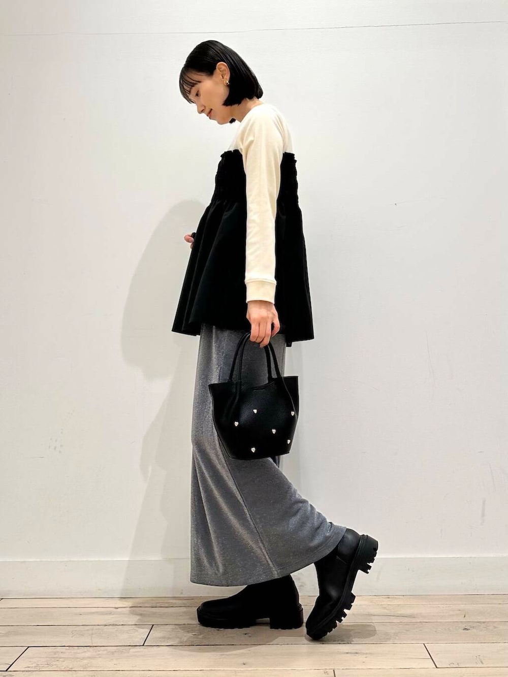 グレー系のその他アウター、ブラック系のブーツ、グレー系のスカートを着用したレディースの冬コーディネートの2枚目の写真