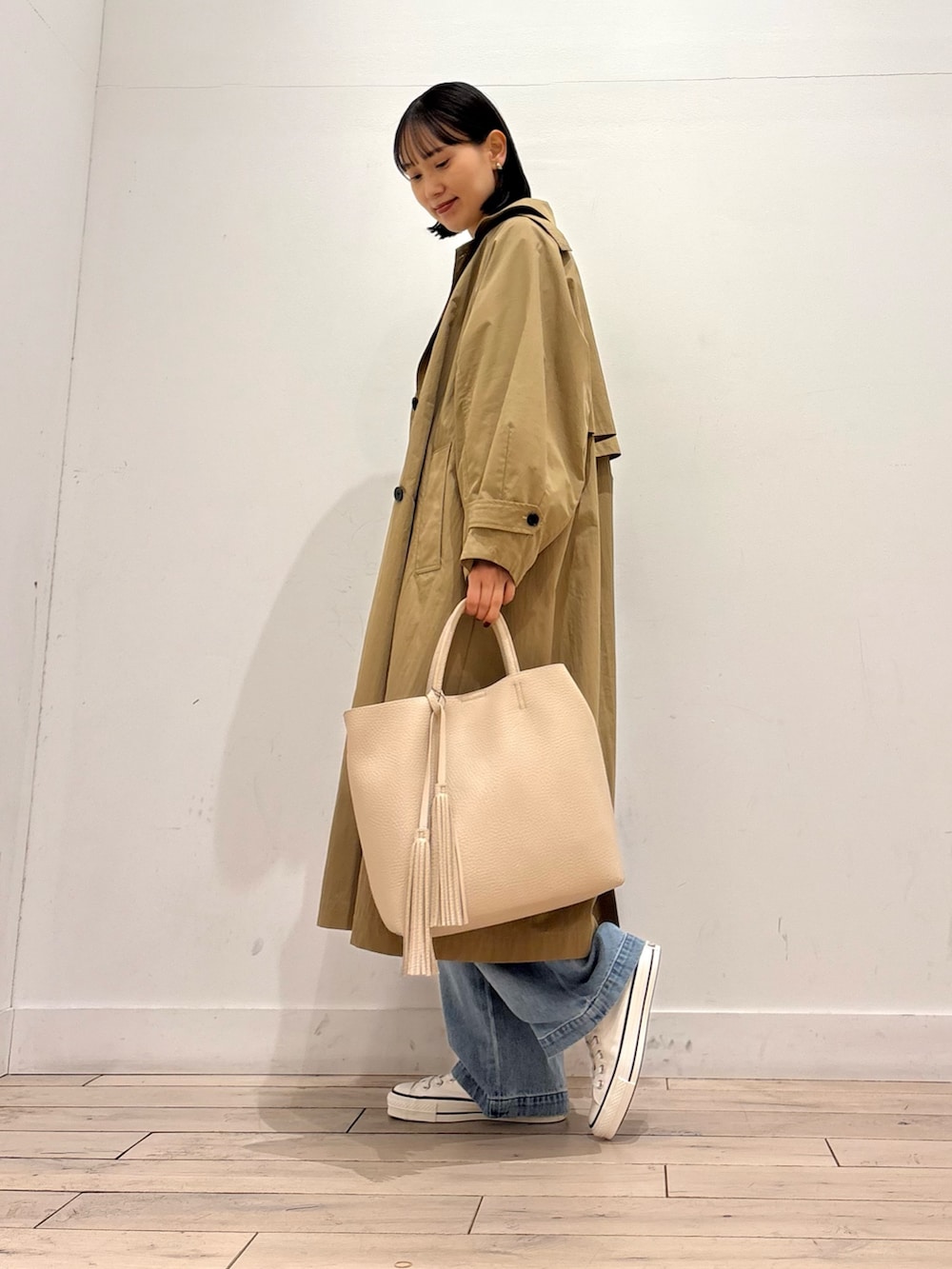 ホワイト系のTシャツ/カットソー、ブルー系のデニムパンツ、ベージュ系のトレンチコートを着用したレディースの春コーディネートの3枚目の写真