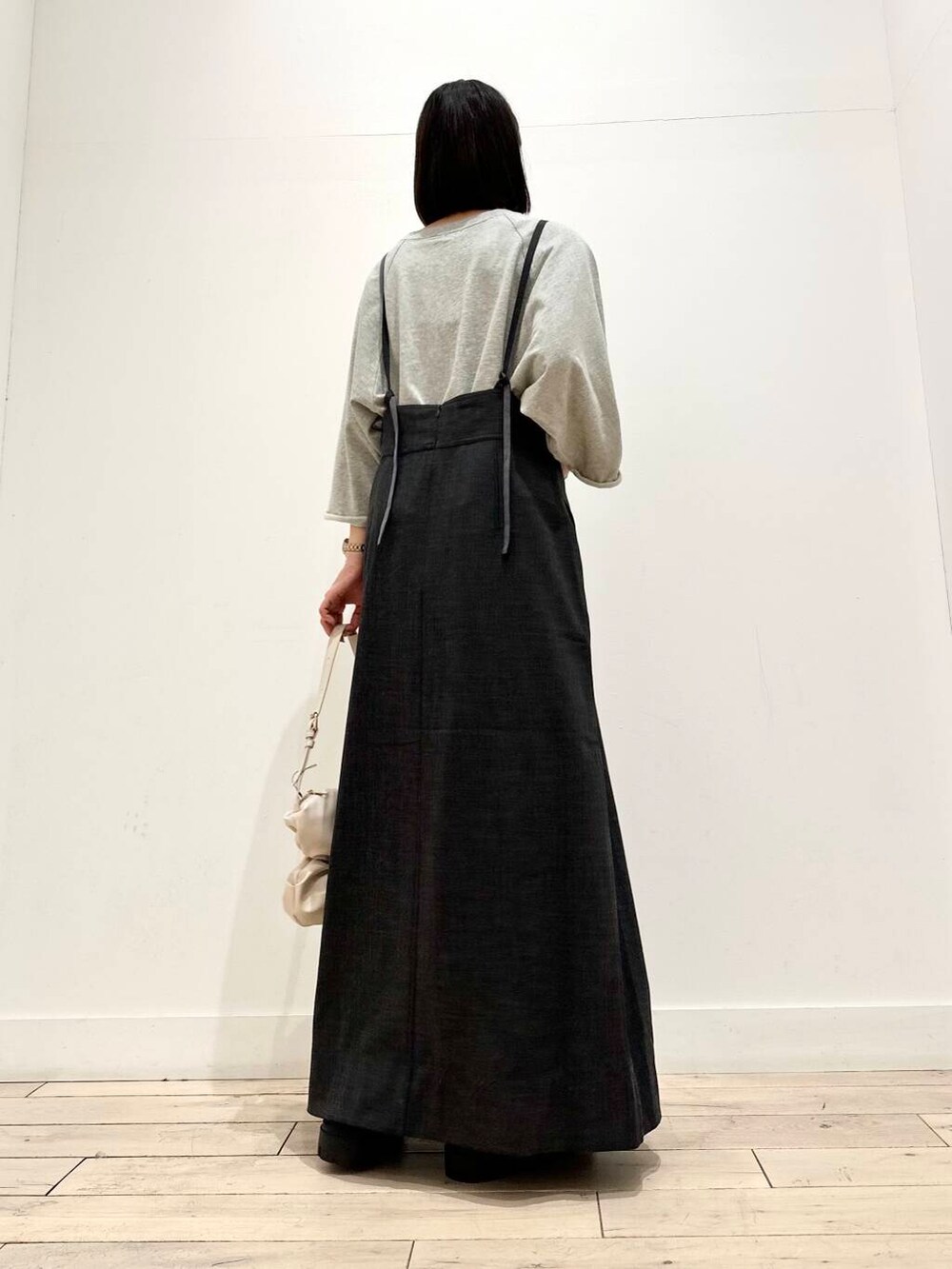 グレー系のTシャツ/カットソー、ホワイト系のハンドバッグ、ブラック系のブーツを着用したレディースの秋コーディネートの3枚目の写真