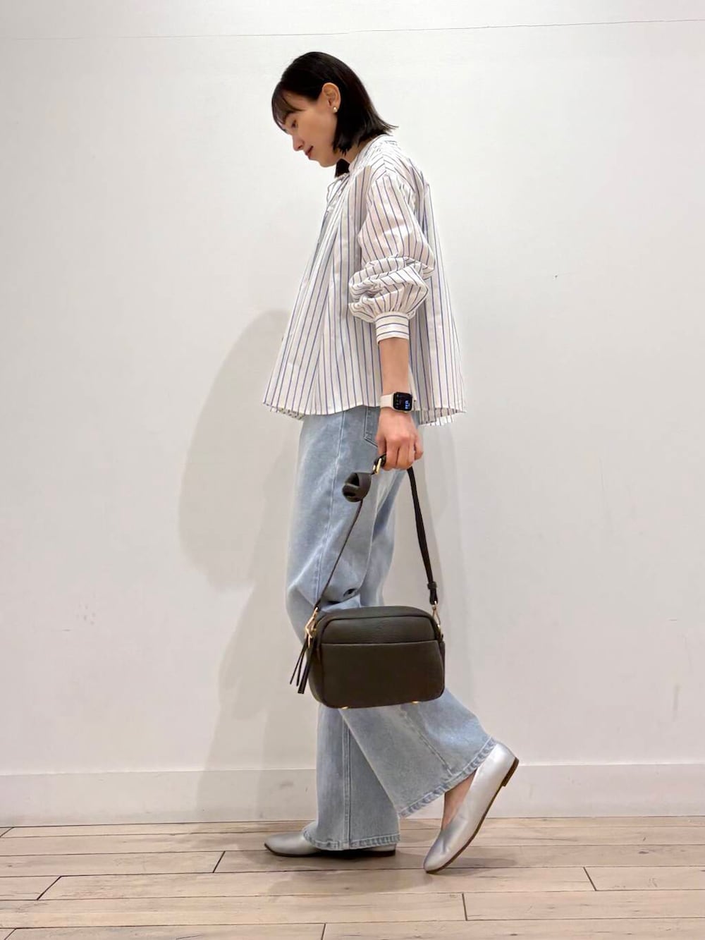 グリーン系のショルダーバッグ、シルバー系のパンプス、ブルー系のデニムパンツを着用したレディースの春コーディネートの3枚目の写真
