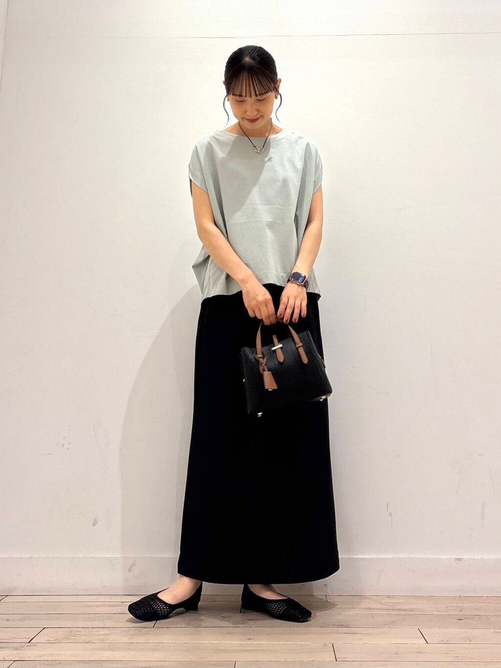 ブラック系のハンドバッグ、グリーン系のTシャツ/カットソー、ブラック系のバレエシューズを着用したレディースの夏コーディネートの2枚目の写真