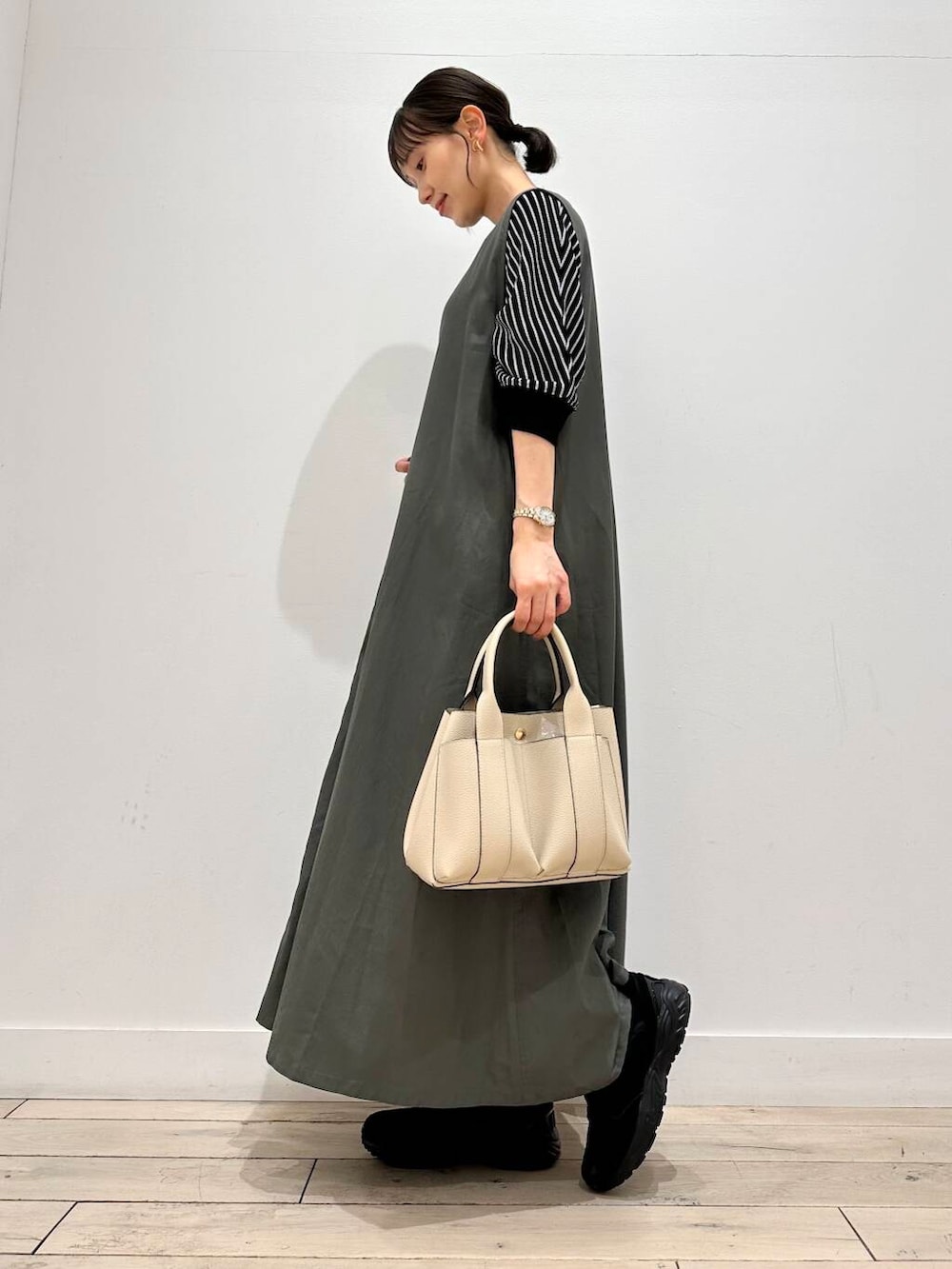 ホワイト系のトートバッグ、ブラック系のスニーカー、ブラック系のTシャツ/カットソーを着用したレディースの夏コーディネートの2枚目の写真