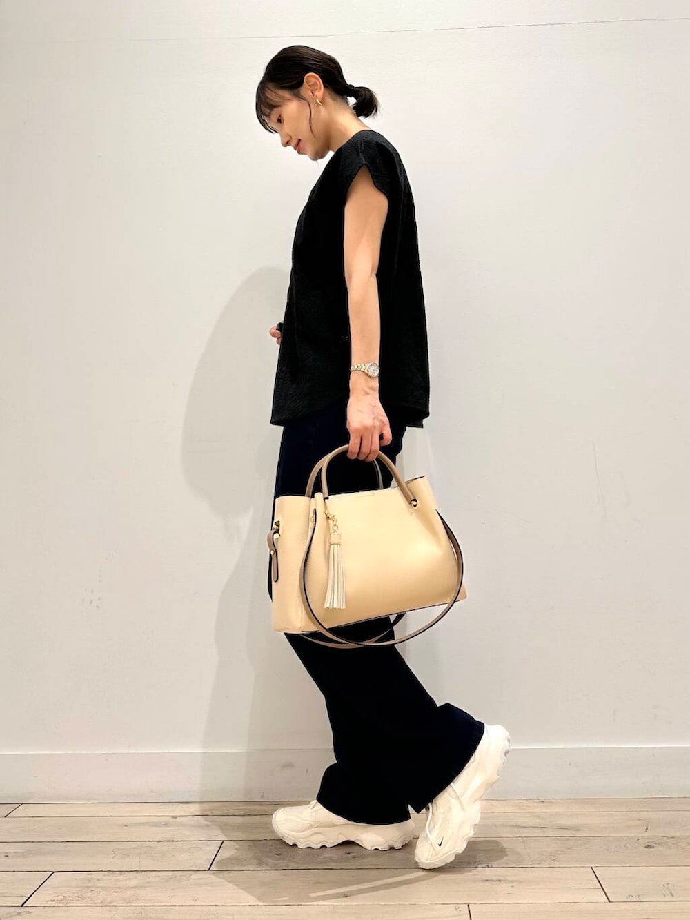 ホワイト系のトートバッグ、ホワイト系のスニーカー、ブラック系のシャツ/ブラウスを着用したレディースの夏コーディネートの2枚目の写真