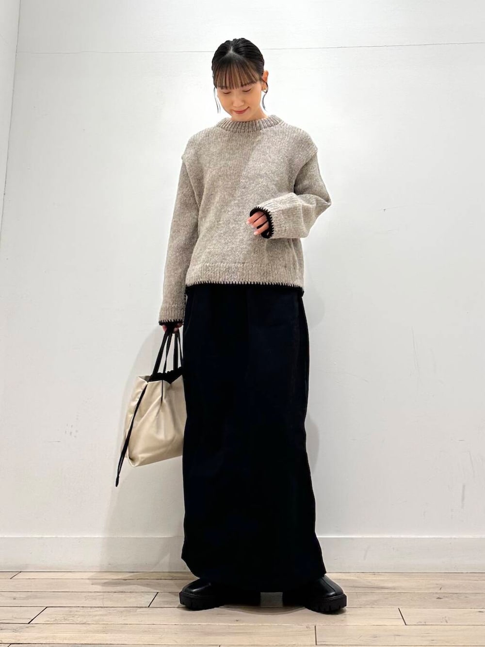 ホワイト系のショルダーバッグ、グレー系のニット/セーター、ブラック系のスカートを着用したレディースの冬コーディネートの2枚目の写真