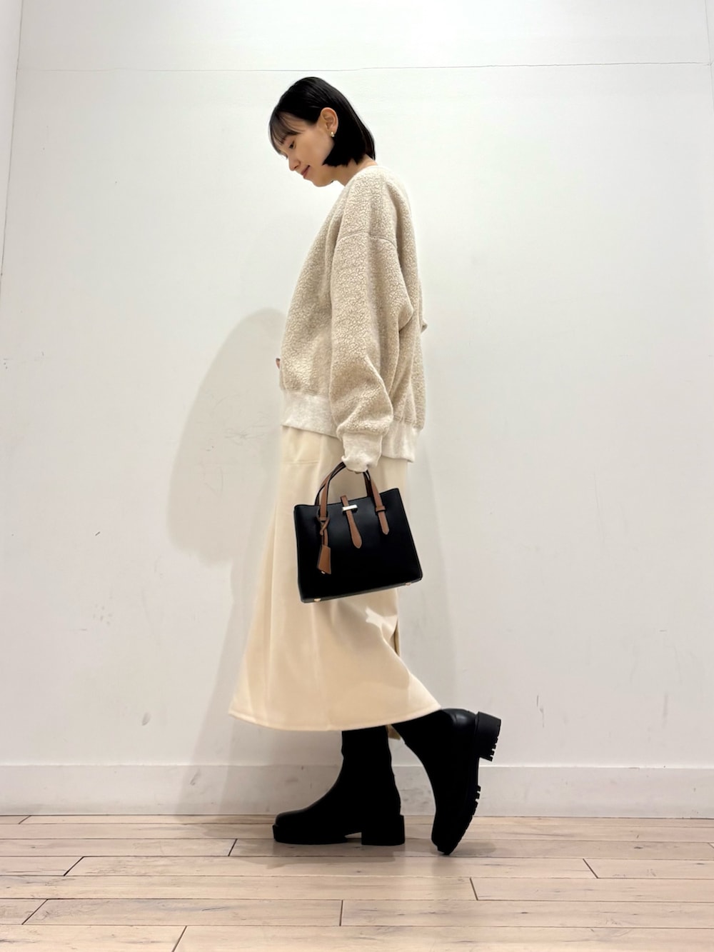 ブラック系のブーツ、ブラック系のハンドバッグ、ホワイト系のスカートを着用したレディースの冬コーディネートの6枚目の写真
