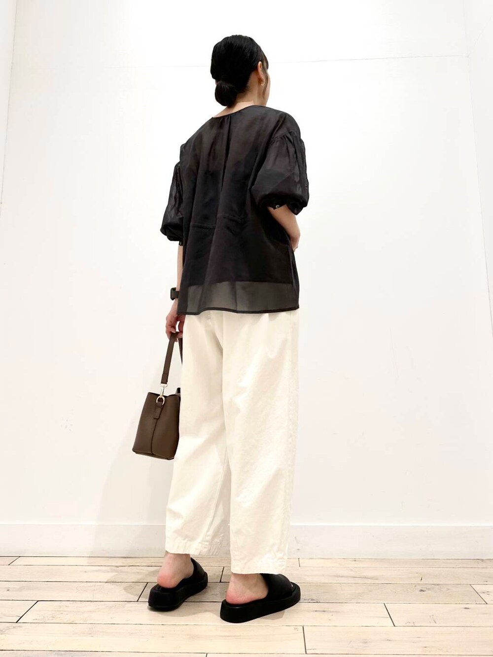 ホワイト系のその他パンツ、ブラック系のサンダル、ブラウン系のショルダーバッグを着用したレディースの夏コーディネートの3枚目の写真