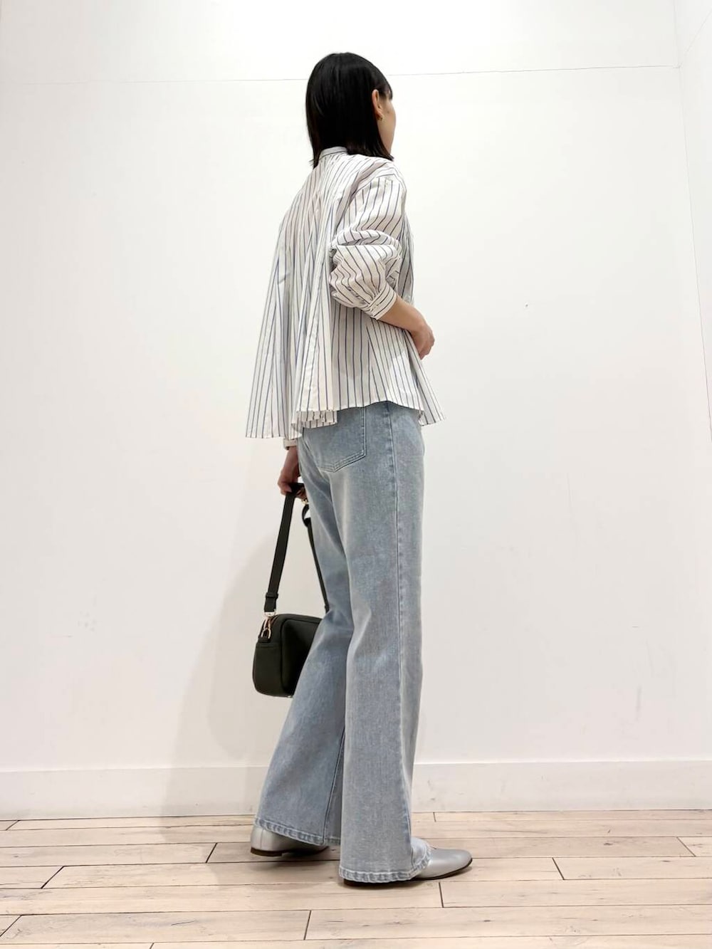 グリーン系のショルダーバッグ、シルバー系のパンプス、ブルー系のデニムパンツを着用したレディースの春コーディネートの4枚目の写真