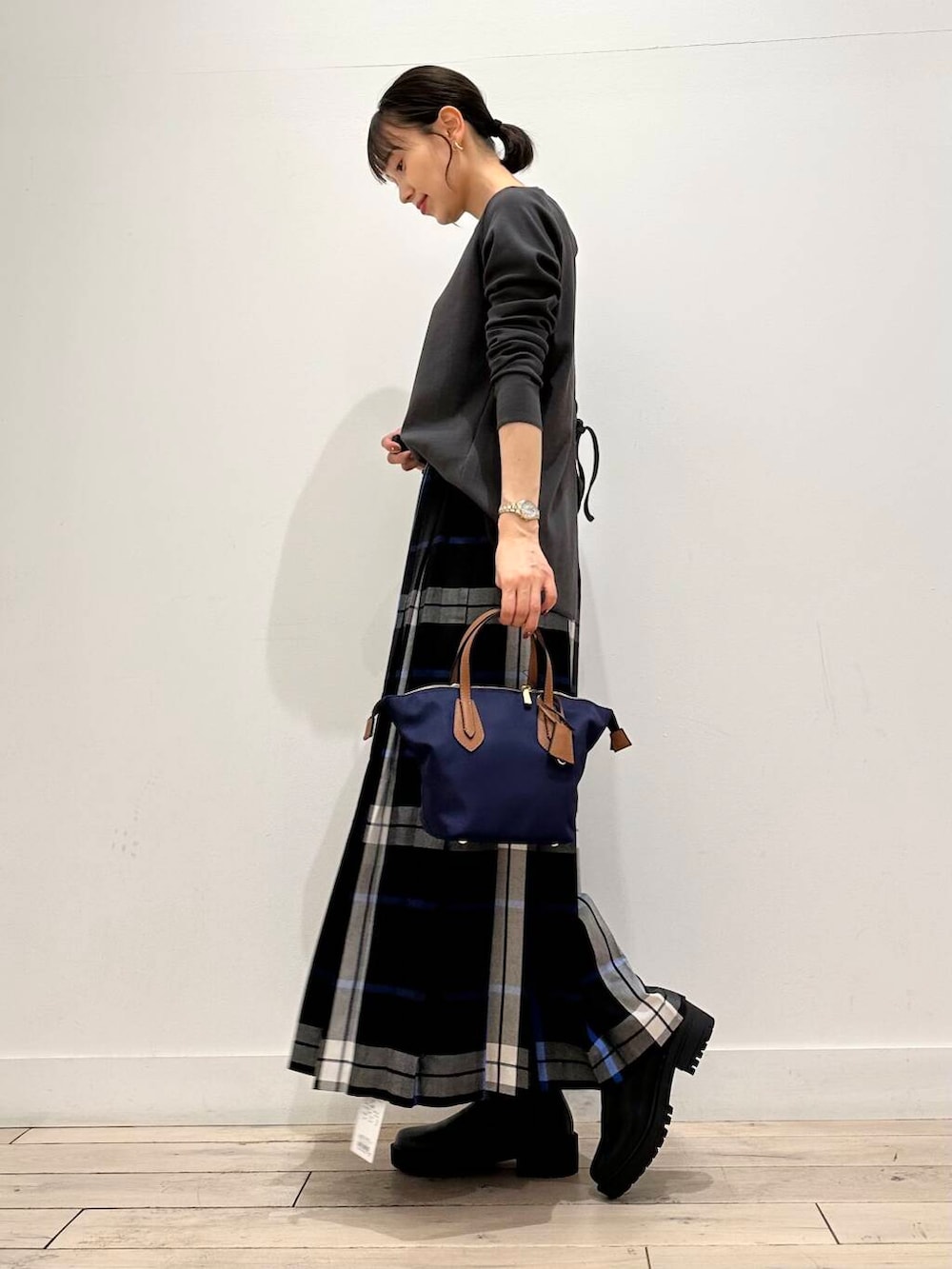 ブルー系のトートバッグ、ブラック系のブーツ、ブラック系のスカートを着用したレディースの夏コーディネートの3枚目の写真