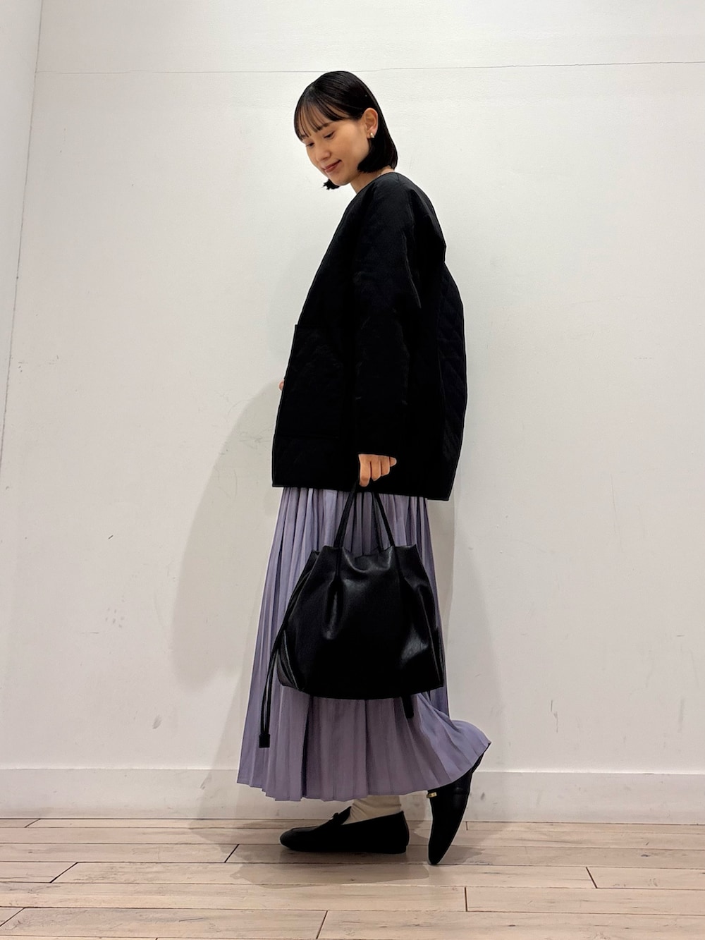 ブラック系のダウンジャケット/コート、グレー系のニット/セーター、パープル系のスカートを着用したレディースの春コーディネートの3枚目の写真