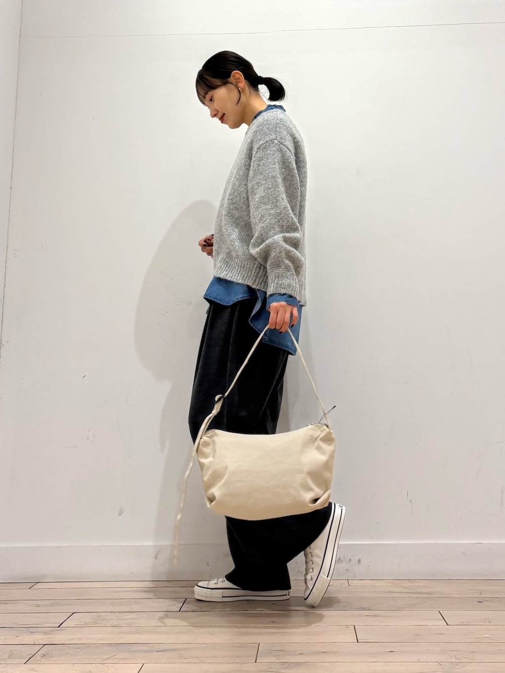 グレー系のニット/セーター、ブルー系のシャツ/ブラウス、ホワイト系のスニーカーを着用したレディースの冬コーディネートの3枚目の写真