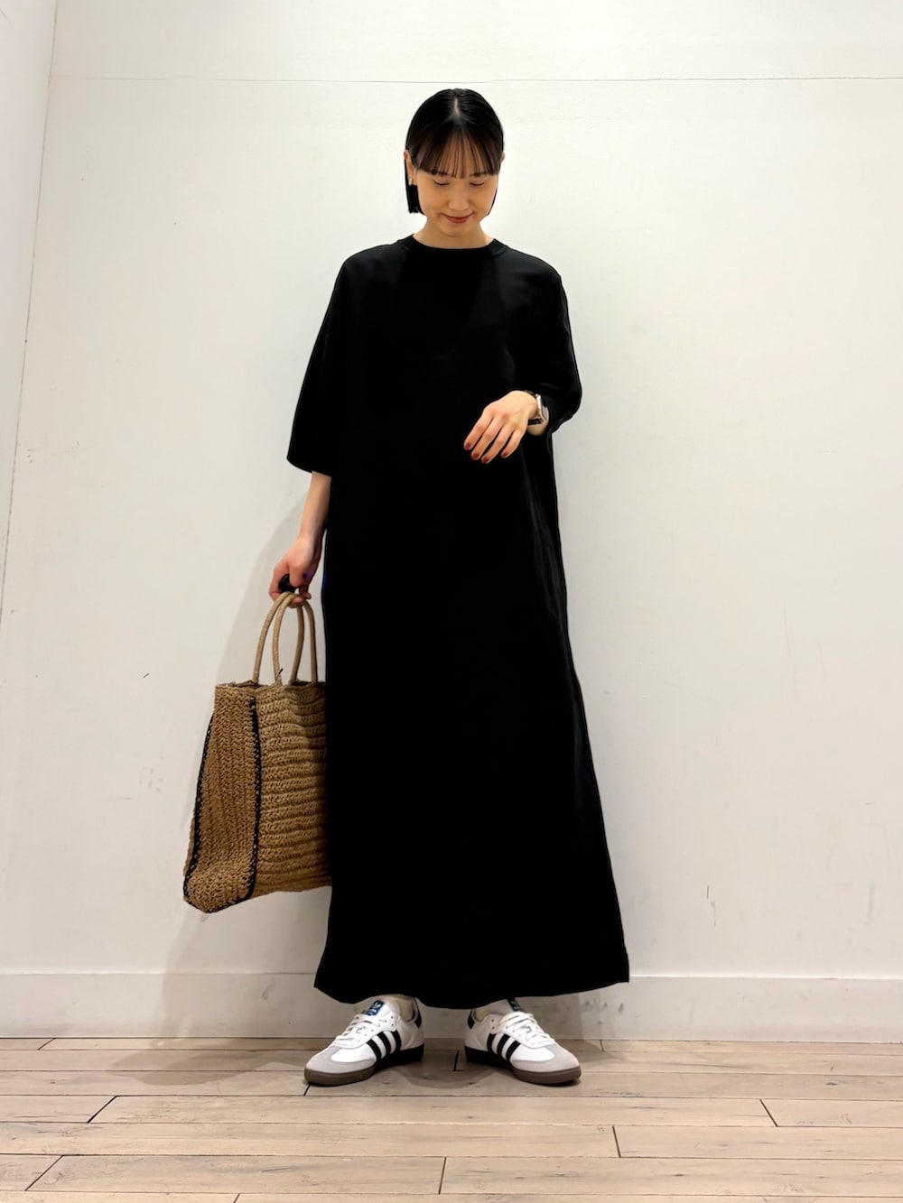 ブラック系のワンピース、ベージュ系のトートバッグ、ホワイト系のスニーカーを着用したレディースの春コーディネートの3枚目の写真