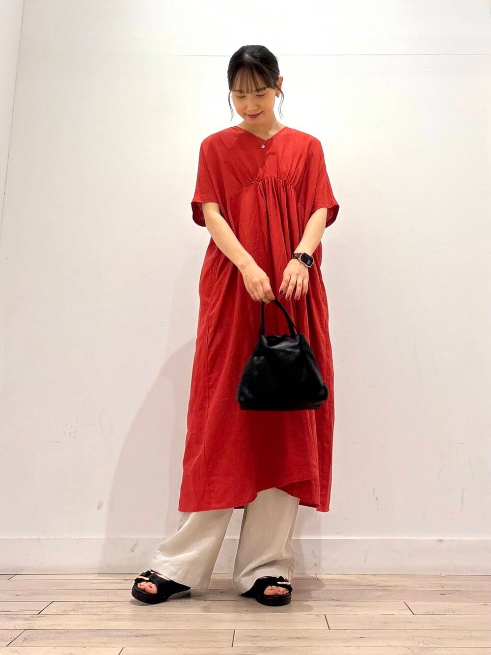 ブラック系のショルダーバッグ、ブラック系のサンダル、レッド系のワンピースを着用したレディースの夏コーディネートの2枚目の写真