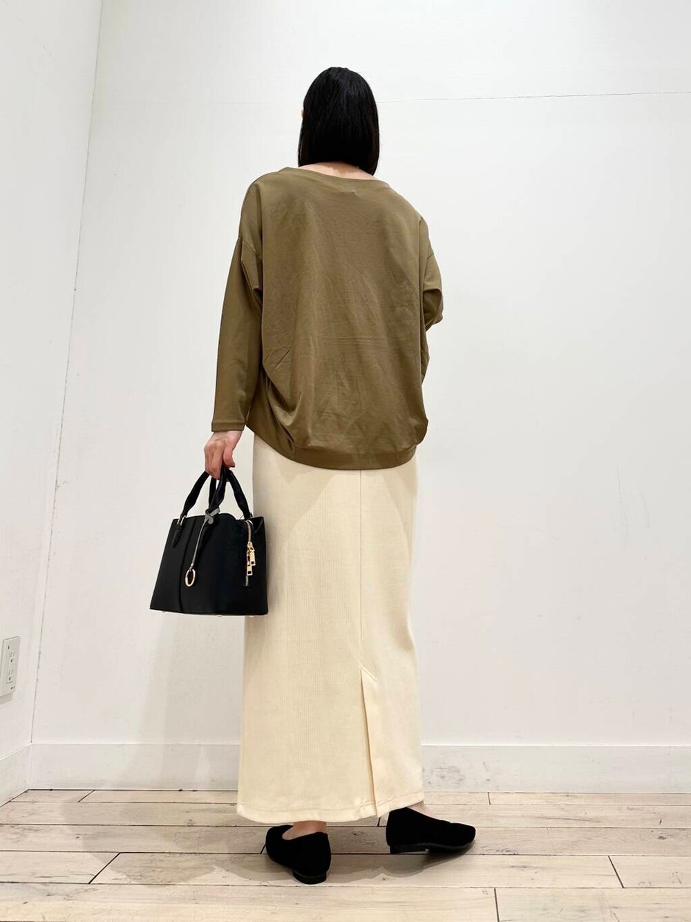 ホワイト系のスカート、ベージュ系のTシャツ/カットソー、ブラック系のハンドバッグを着用したレディースの秋コーディネートの3枚目の写真