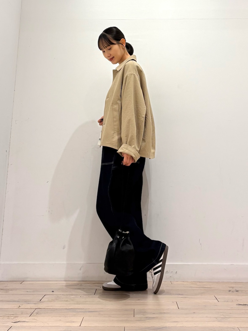 ベージュ系のステンカラーコート、ホワイト系のTシャツ/カットソー、ブルー系のデニムパンツを着用したレディースの秋コーディネートの3枚目の写真