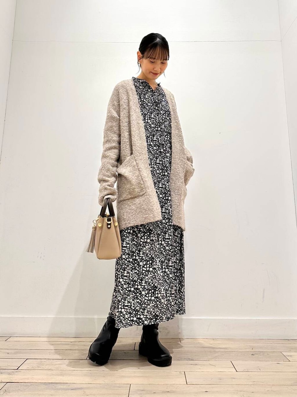 ベージュ系のトートバッグ、ブラック系のブーツ、ベージュ系のカーディガン/ボレロを着用したレディースの冬コーディネートの2枚目の写真