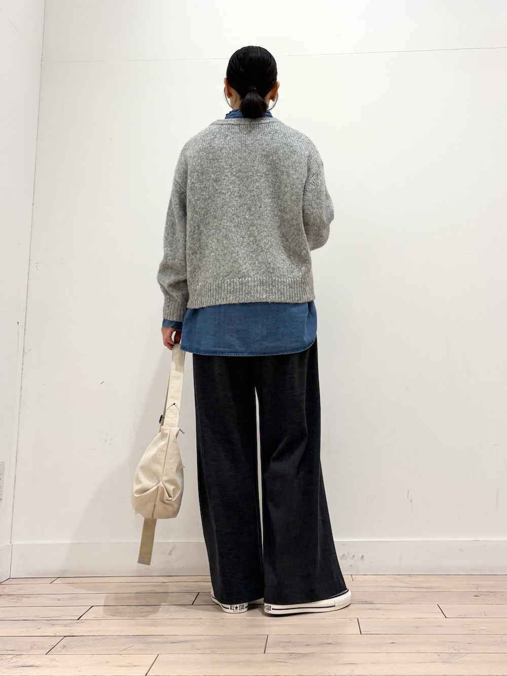 グレー系のニット/セーター、ブルー系のシャツ/ブラウス、ホワイト系のスニーカーを着用したレディースの冬コーディネートの4枚目の写真