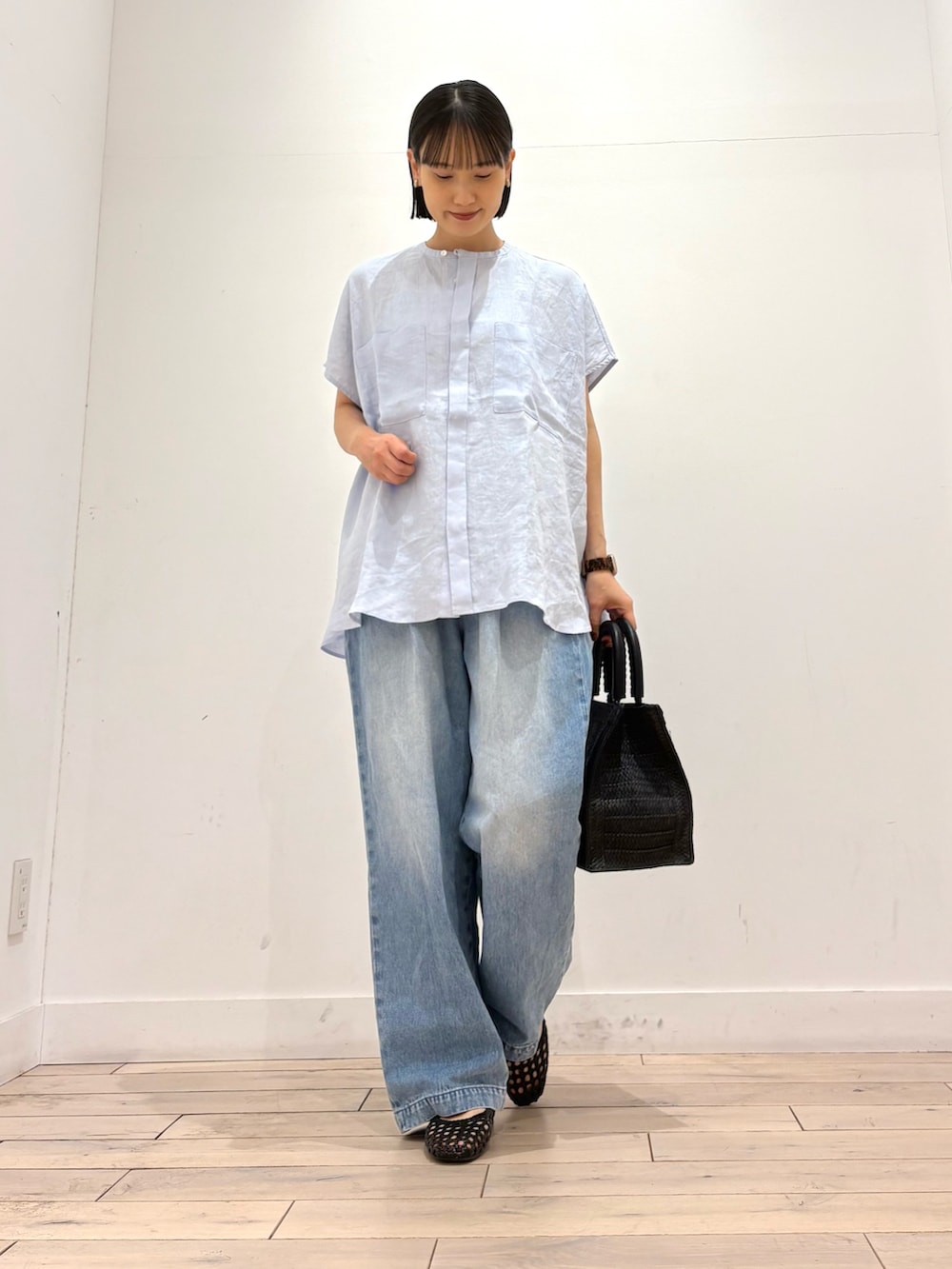ブルー系のシャツ/ブラウス、ブルー系のデニムパンツ、ブラック系のハンドバッグを着用したレディースの春コーディネートの2枚目の写真