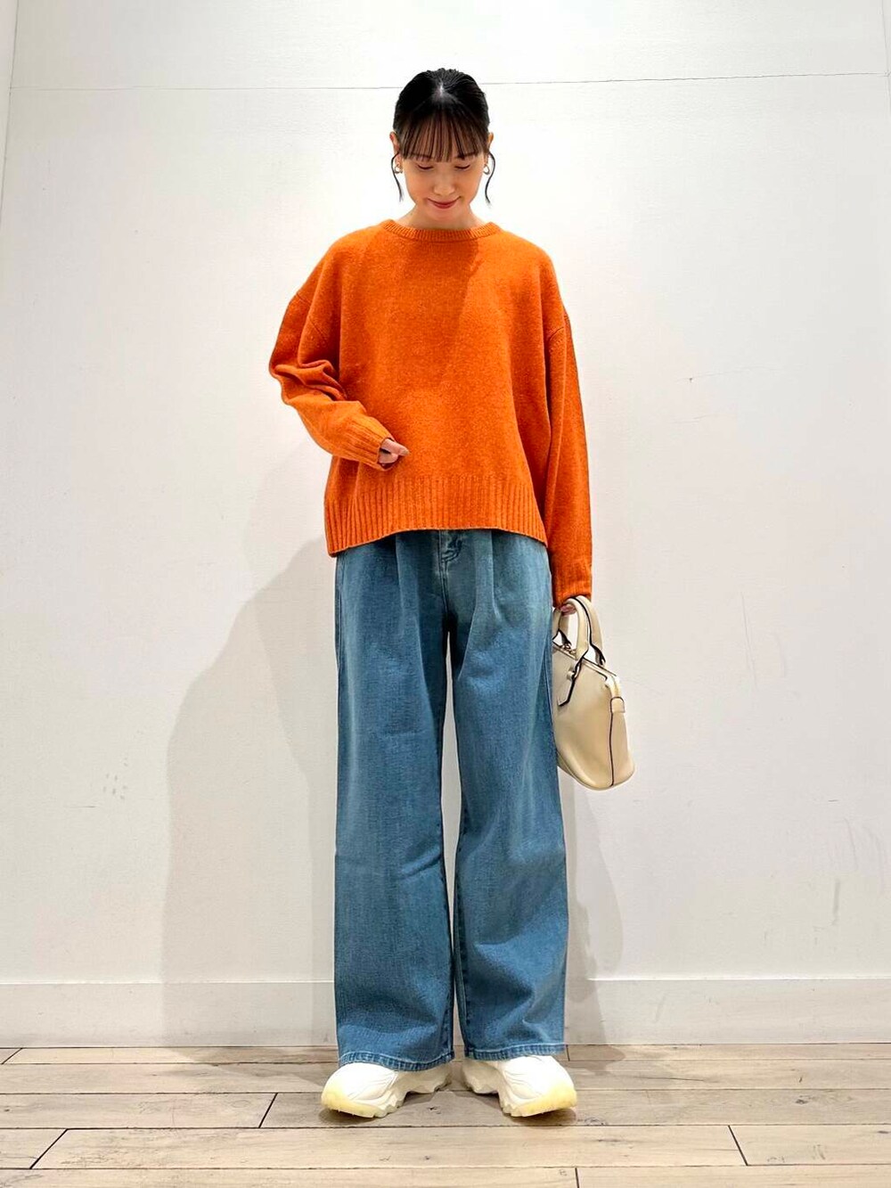 ホワイト系のスニーカー、オレンジ系のニット/セーター、ホワイト系のボストンバッグを着用したレディースの冬コーディネートの3枚目の写真