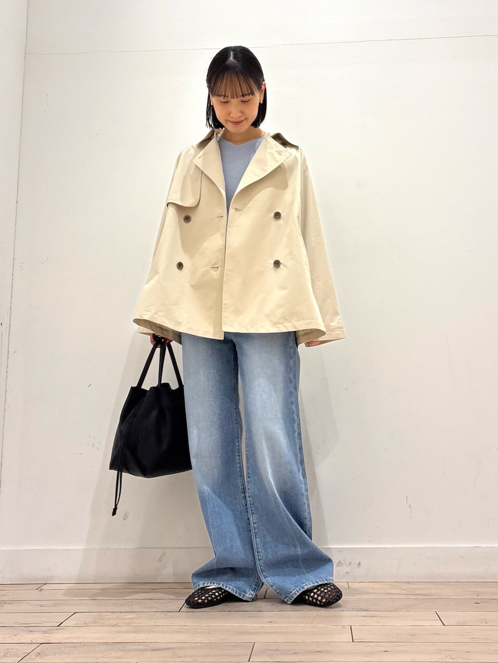 ベージュ系のトレンチコート、ブルー系のニット/セーター、ブラック系のサンダルを着用したレディースの春コーディネートの2枚目の写真