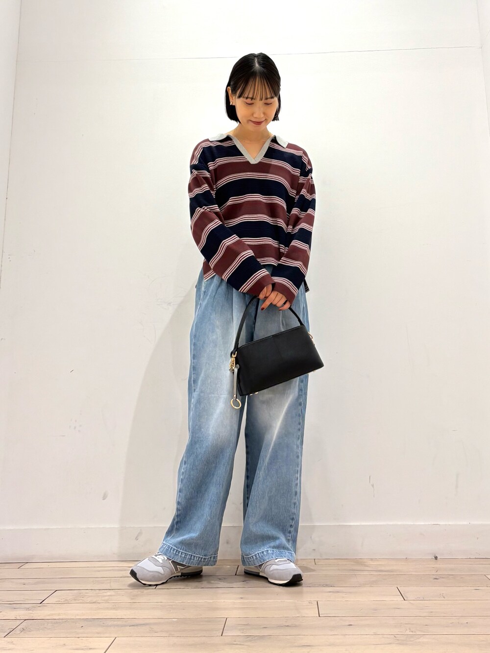 ブルー系のニット/セーター、ブルー系のデニムパンツ、ブラック系のショルダーバッグを着用したレディースの秋コーディネートの3枚目の写真